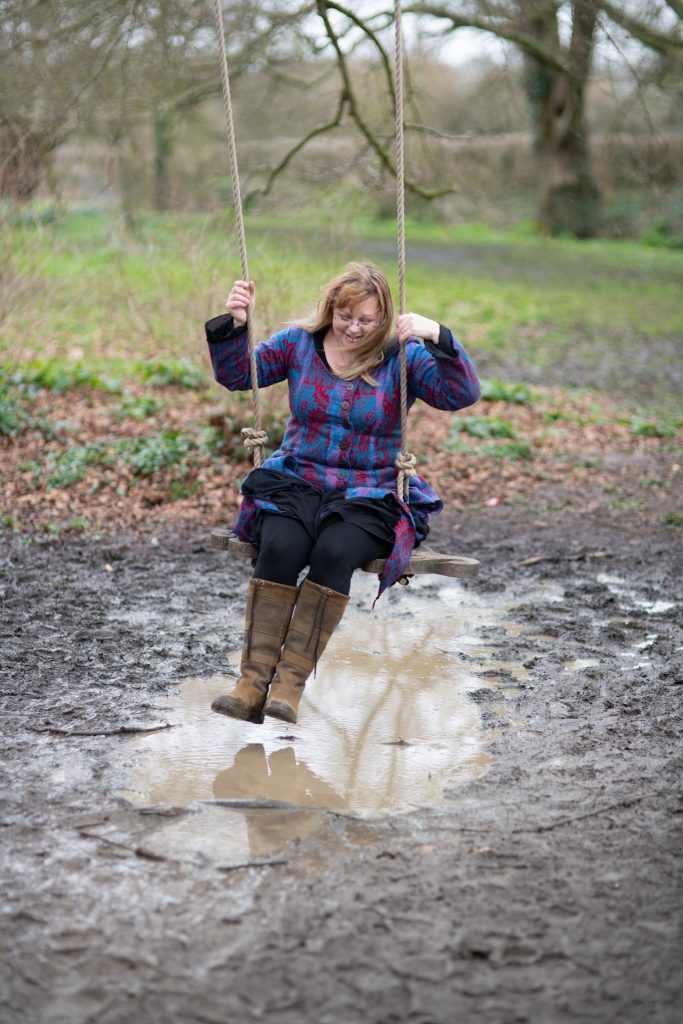 Over thirty style blogger wearing a hippy coat on a swing