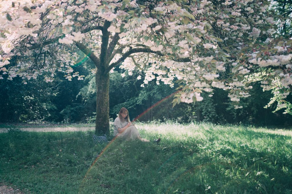 british blogger sitting on the grass under a blossom tree